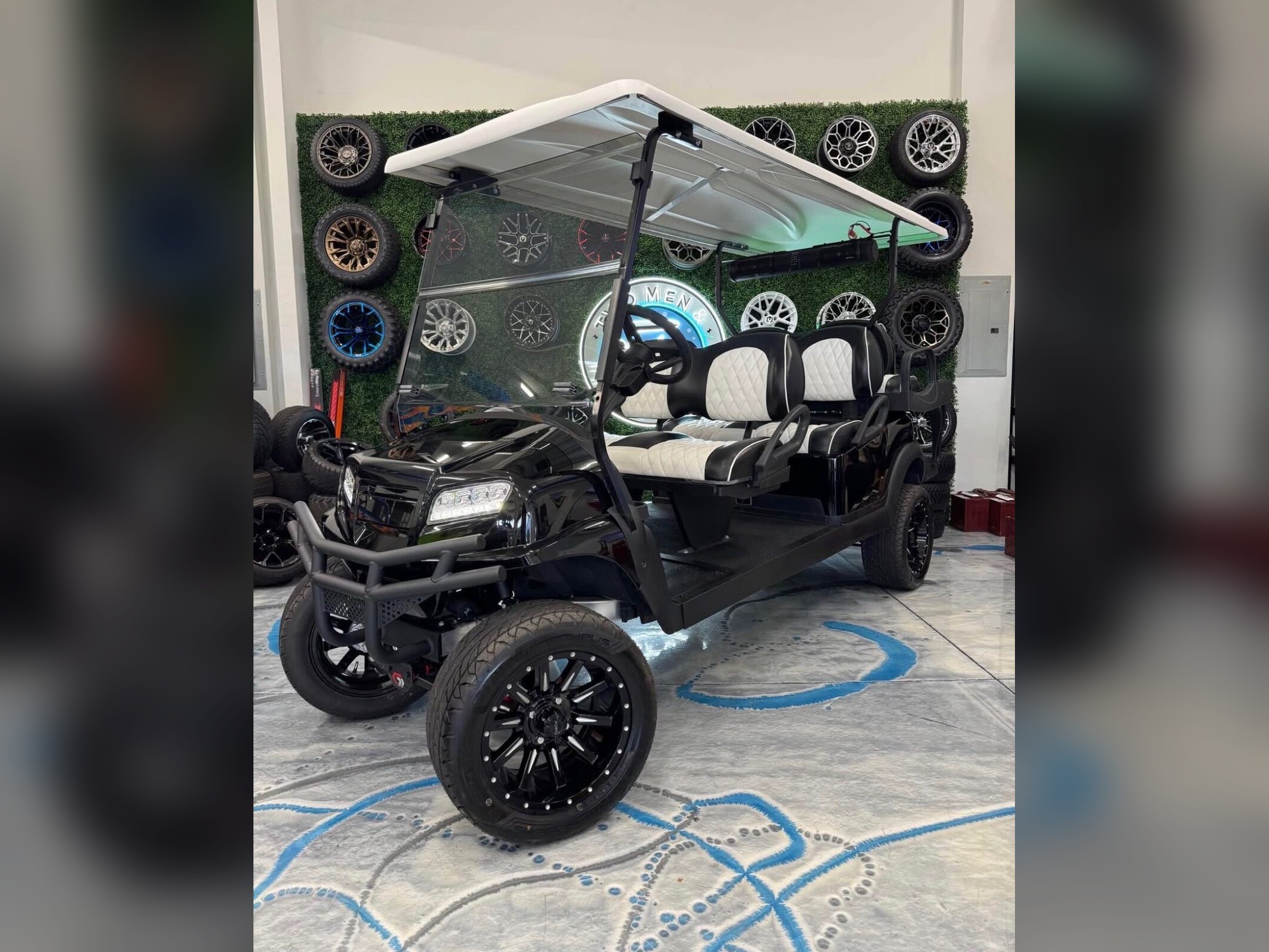 Black six-seater Club Car with white diamond seats and brush guard