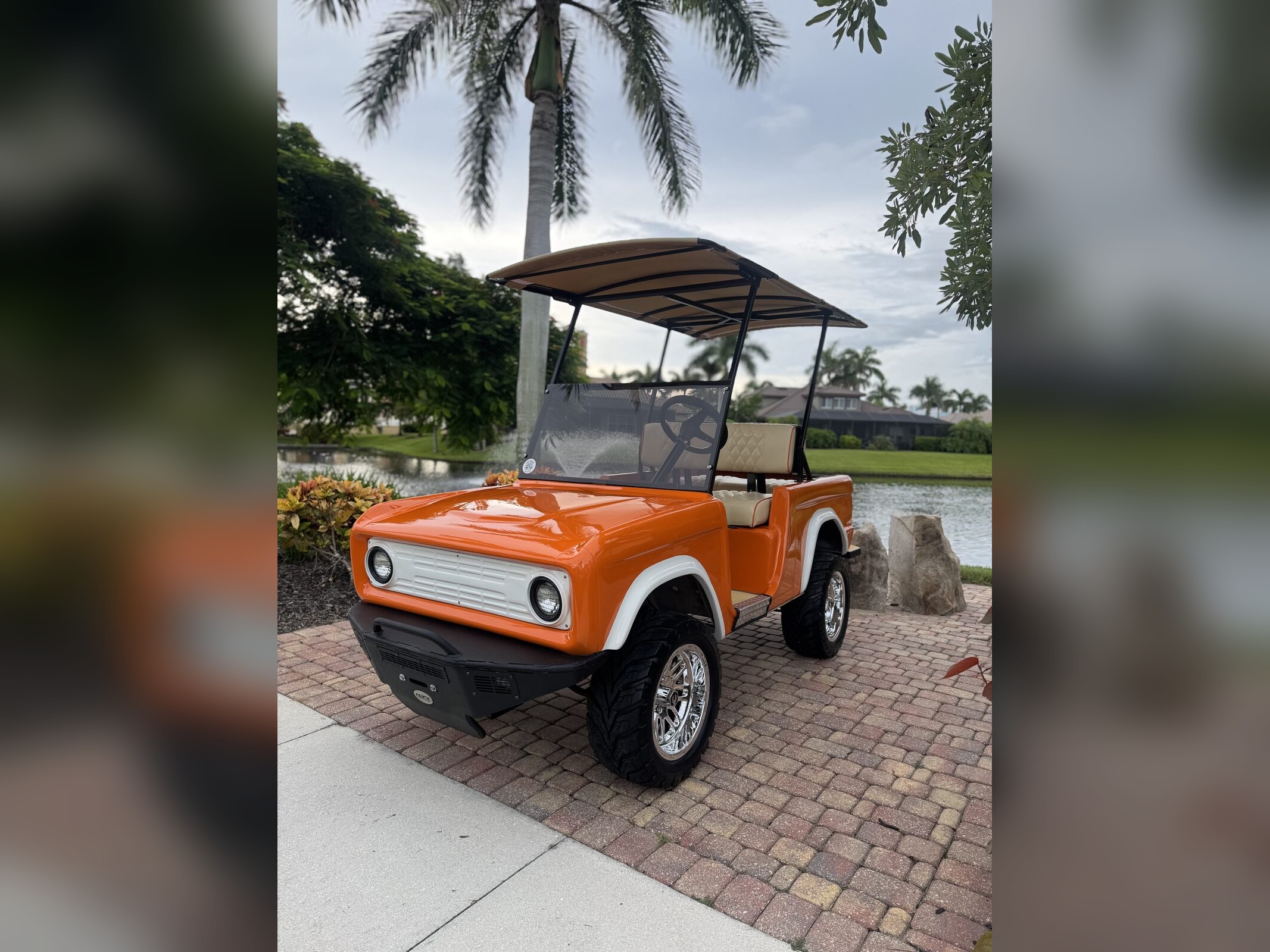 Orange and white classic Bronco-style golf cart by a Cape Coral lake at sunset