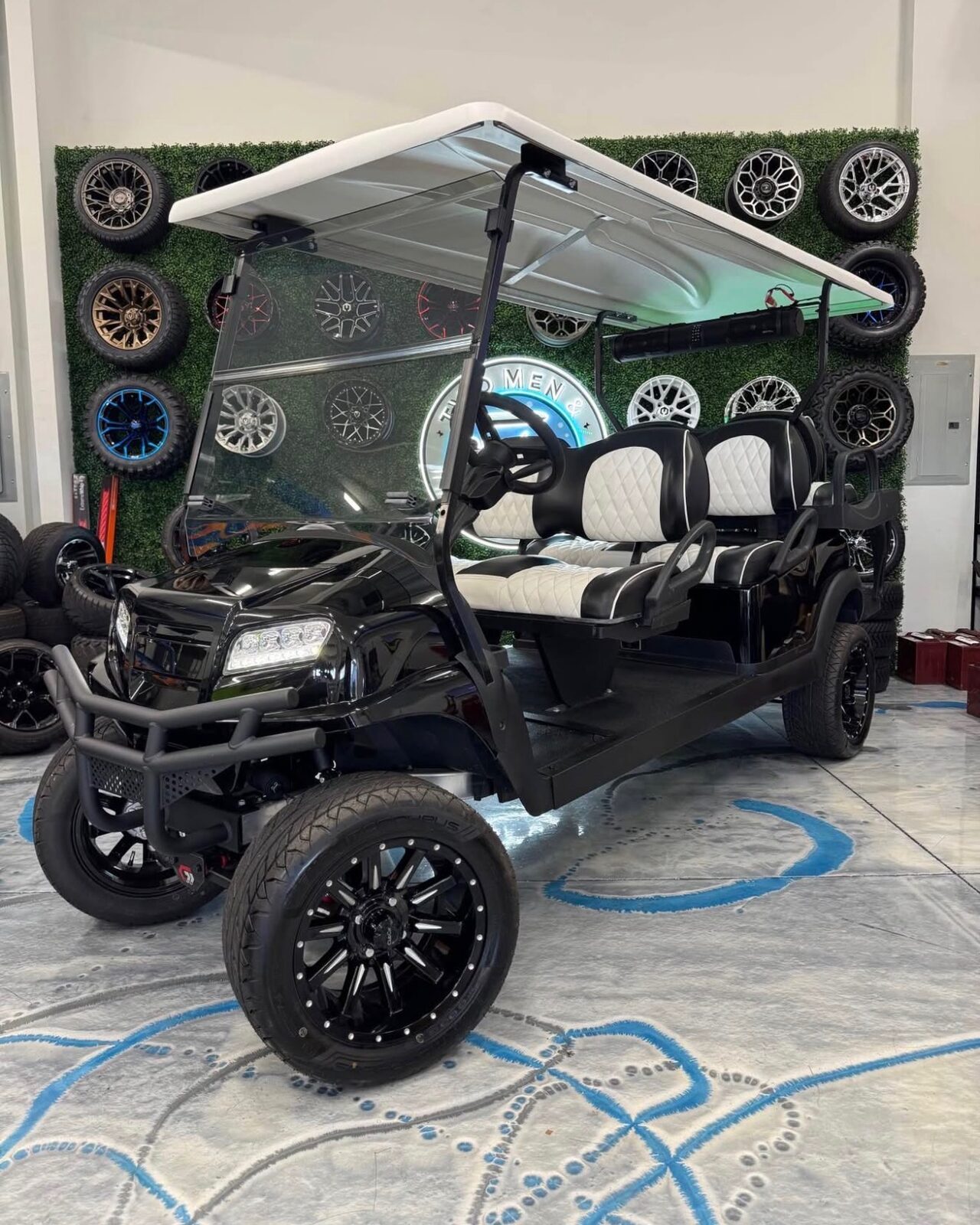 Black six-seater Club Car with white diamond seats and brush guard